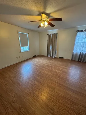 a view of an empty room with wooden floor and a window