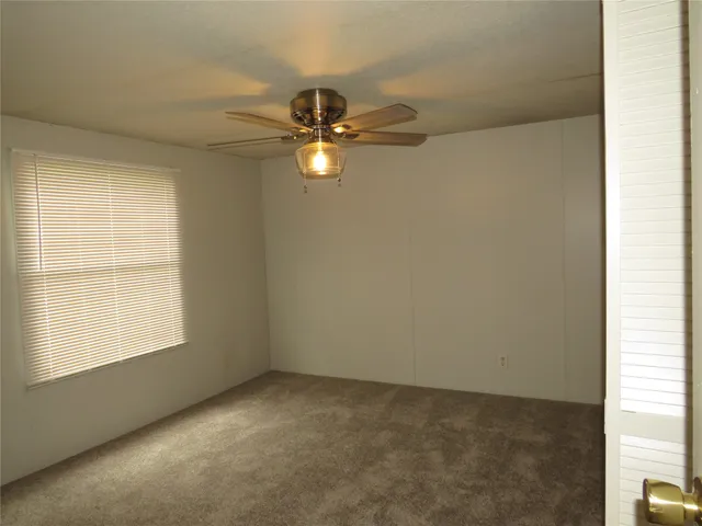 an empty room with a window and a fan