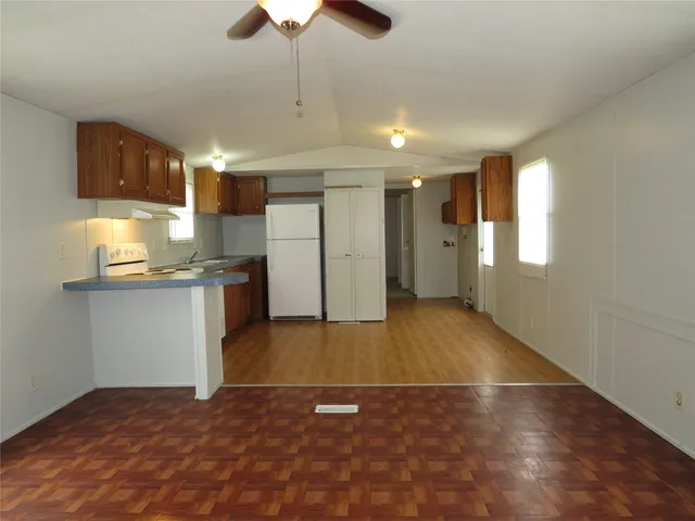 a view of kitchen and empty room with wooden floor