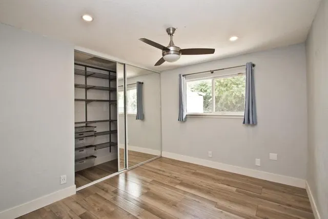 a view of an empty room with a window and wooden floor