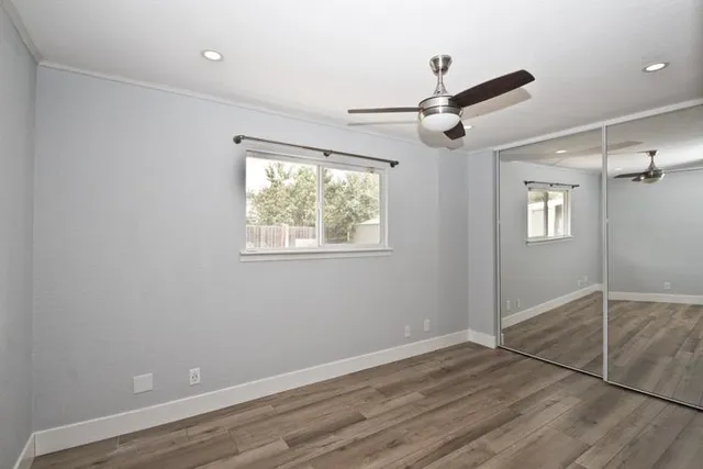 a view of empty room with wooden floor and fan