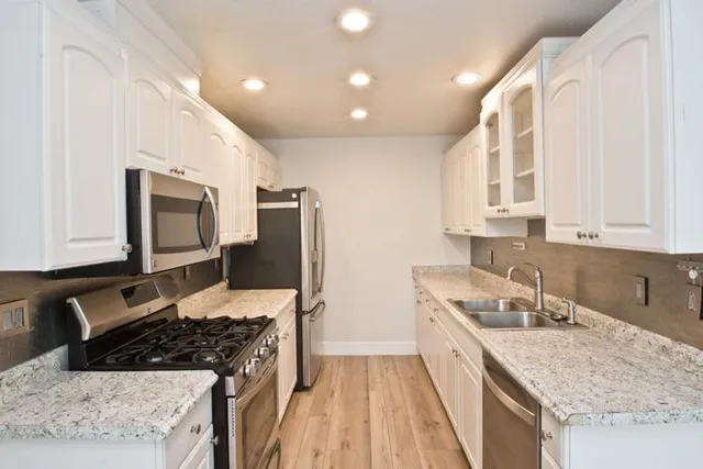 a kitchen with stainless steel appliances granite countertop a sink stove and refrigerator