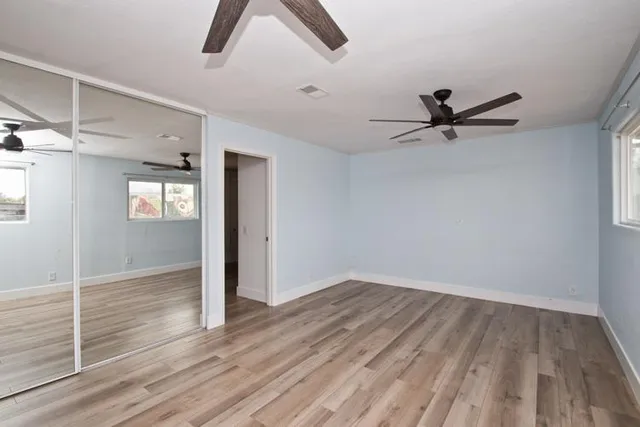 an empty room with wooden floor and windows