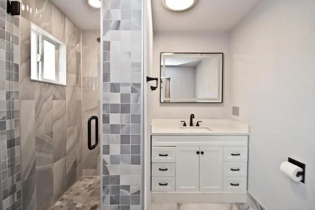 a bathroom with a granite countertop sink a mirror and shower