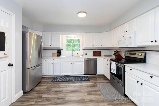 a kitchen with granite countertop white cabinets and white appliances