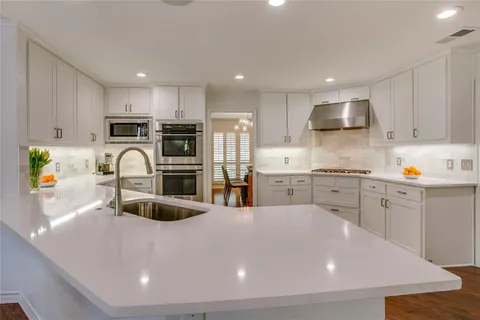 a kitchen with stainless steel appliances a stove a sink a microwave a refrigerator and cabinets