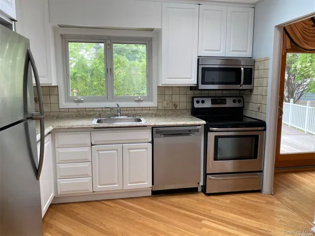 a kitchen with white cabinets stainless steel appliances and a window