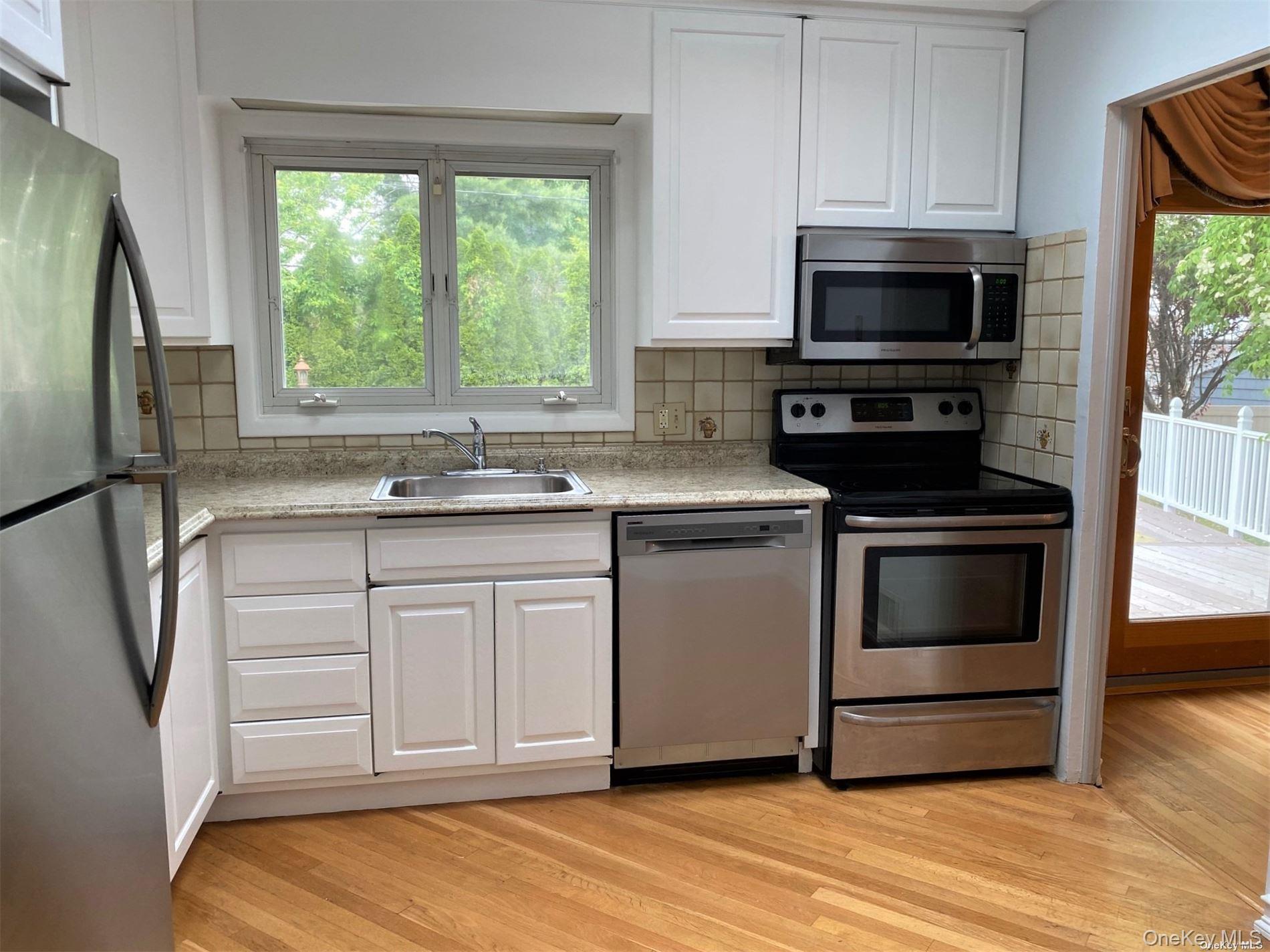 23 Duncan Lane Huntington, NY 11743 - Photo 6 of 25 a kitchen with white cabinets stainless steel appliances and a window