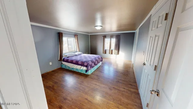 a bedroom with wooden floor and window