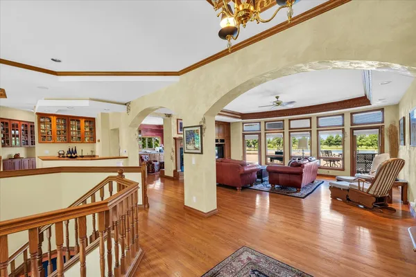 a open kitchen with stainless steel appliances granite countertop a stove dining table chairs and a large window with wooden floor