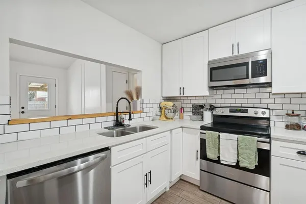 a kitchen with stainless steel appliances granite countertop grey cabinets a stove a sink and dishwasher