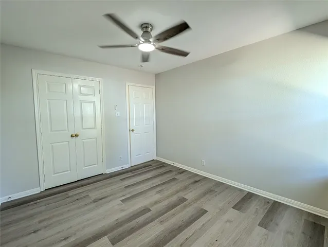 an empty room with wooden floor fan and windows