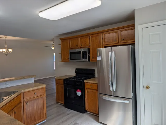 a kitchen with granite countertop stainless steel appliances a sink a stove and a refrigerator