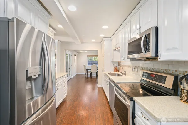 a kitchen with stainless steel appliances a refrigerator a stove top oven and a sink