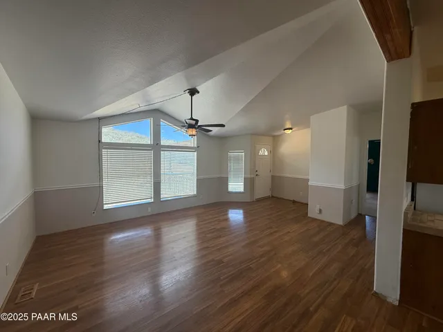 a view of a livingroom with wooden floor a ceiling fan and windows