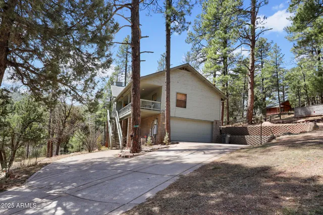 an aerial view of residential house with outdoor space and trees all around