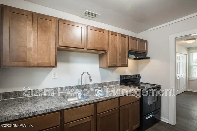a kitchen with granite countertop a sink stove and refrigerator