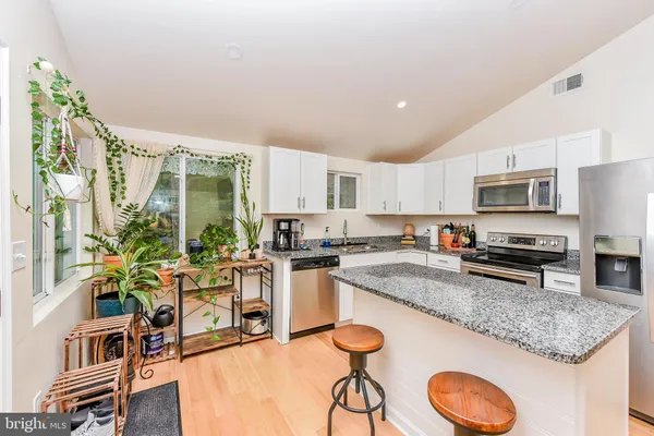 a kitchen with stainless steel appliances granite countertop a stove top oven a sink dishwasher a dining table and chairs with wooden floor