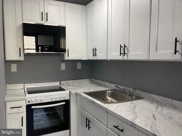 a kitchen with granite countertop white cabinets and a stove a oven with white countertops