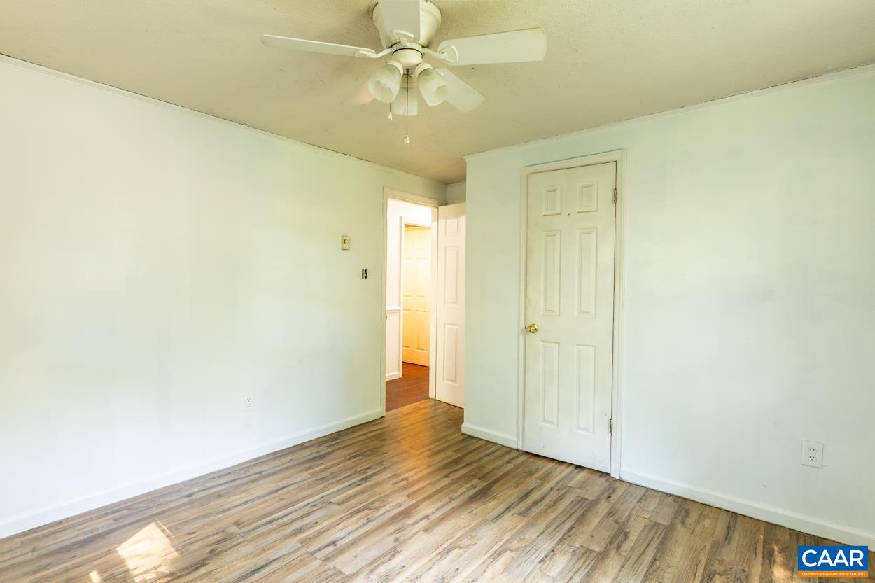 327 Village Road Shipman, VA 22971 - Photo 25 of 48 an empty room with wooden floor and fan