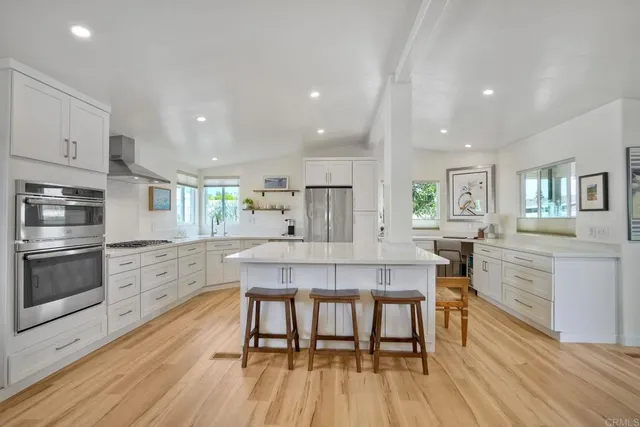 a kitchen with stainless steel appliances kitchen island granite countertop a table chairs sink and cabinets