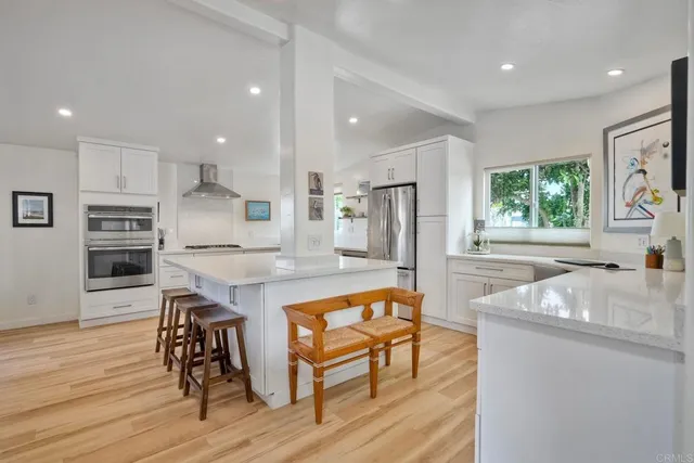 a kitchen with stainless steel appliances granite countertop a kitchen island hardwood floor sink stove dining table and chairs