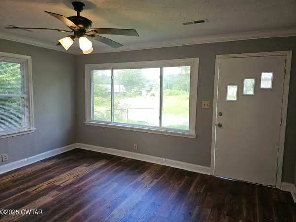 a view of an empty room with wooden floor and a window