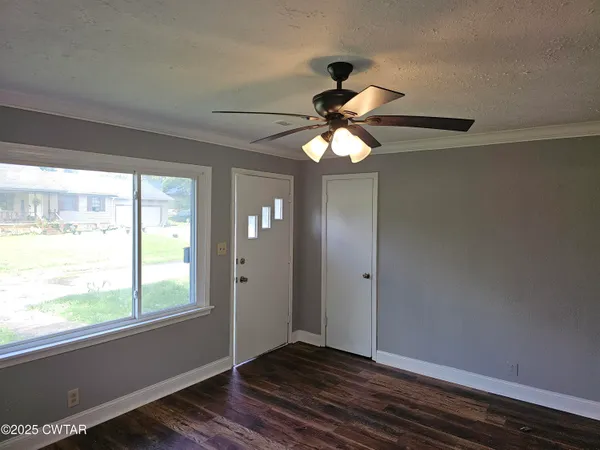 an empty room with wooden floor fan and windows