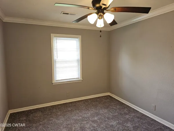 an empty room with a window and a fan