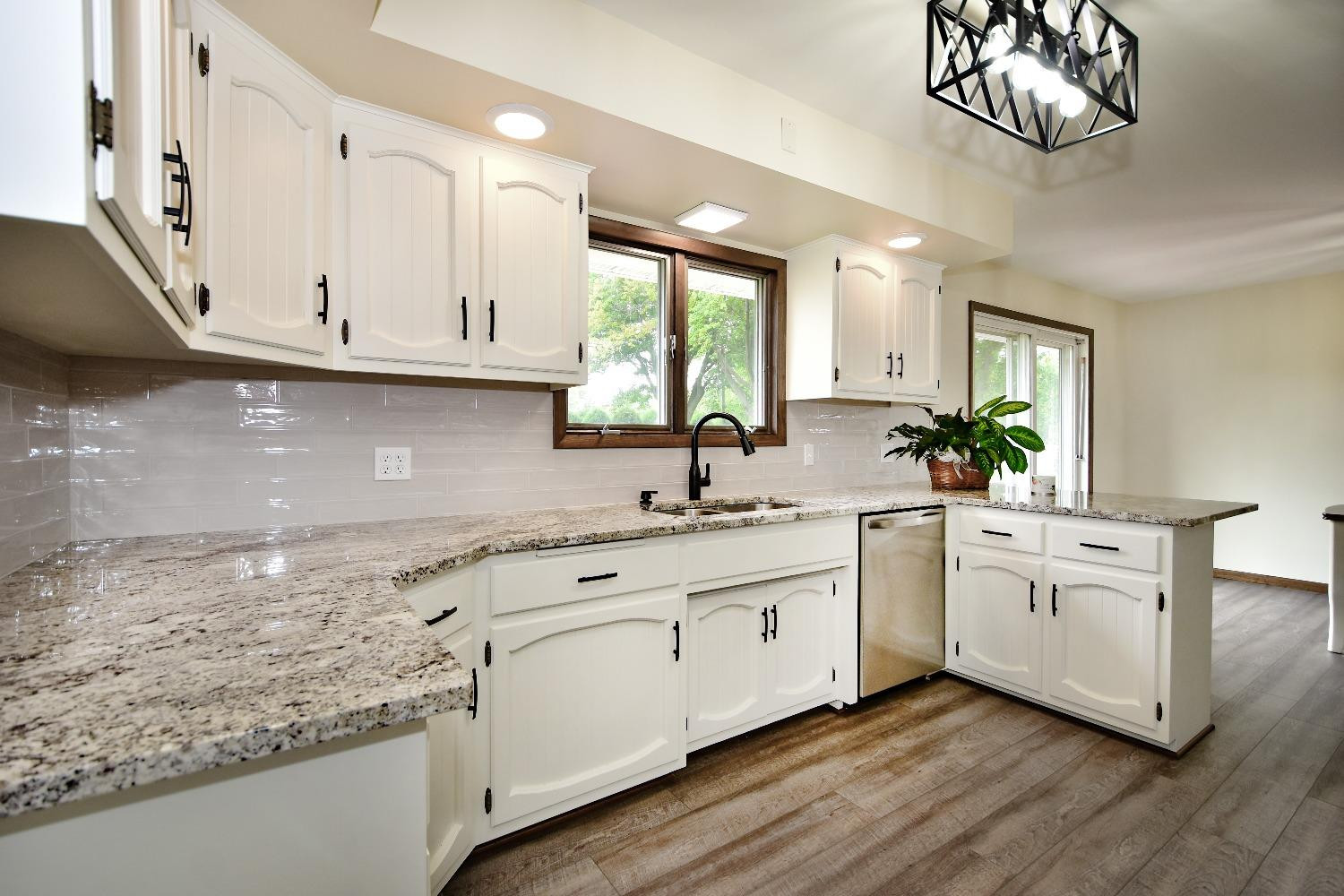9020 Bryan Street Crown Point, IN 46307 - Photo 8 of 31 a kitchen with white cabinets a sink dishwasher and a stove with wooden floor