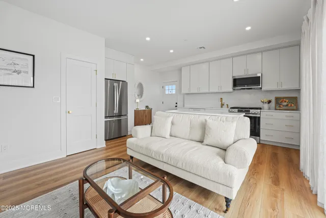 a living room with stainless steel appliances furniture and a wooden floor