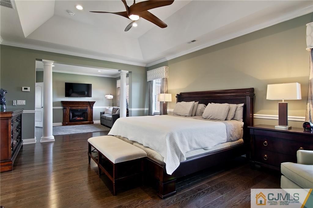 25 Preakness Drive Monroe Township, NJ 08831 - Photo 21 of 48 a bedroom with a large bed a flat tv screen and a fireplace