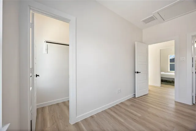 a view of a hallway with wooden floor and a bathroom