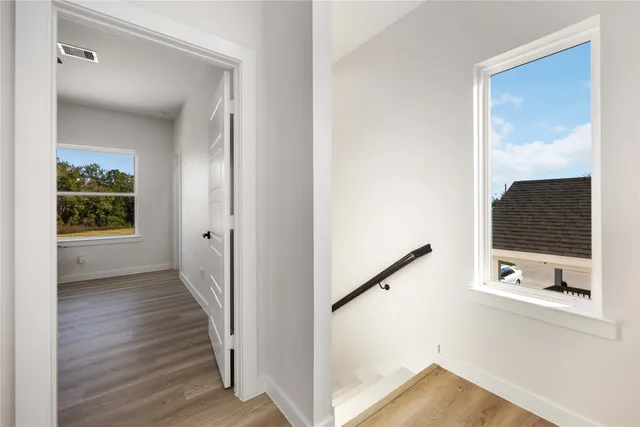 a view of a hallway with wooden floor and staircase