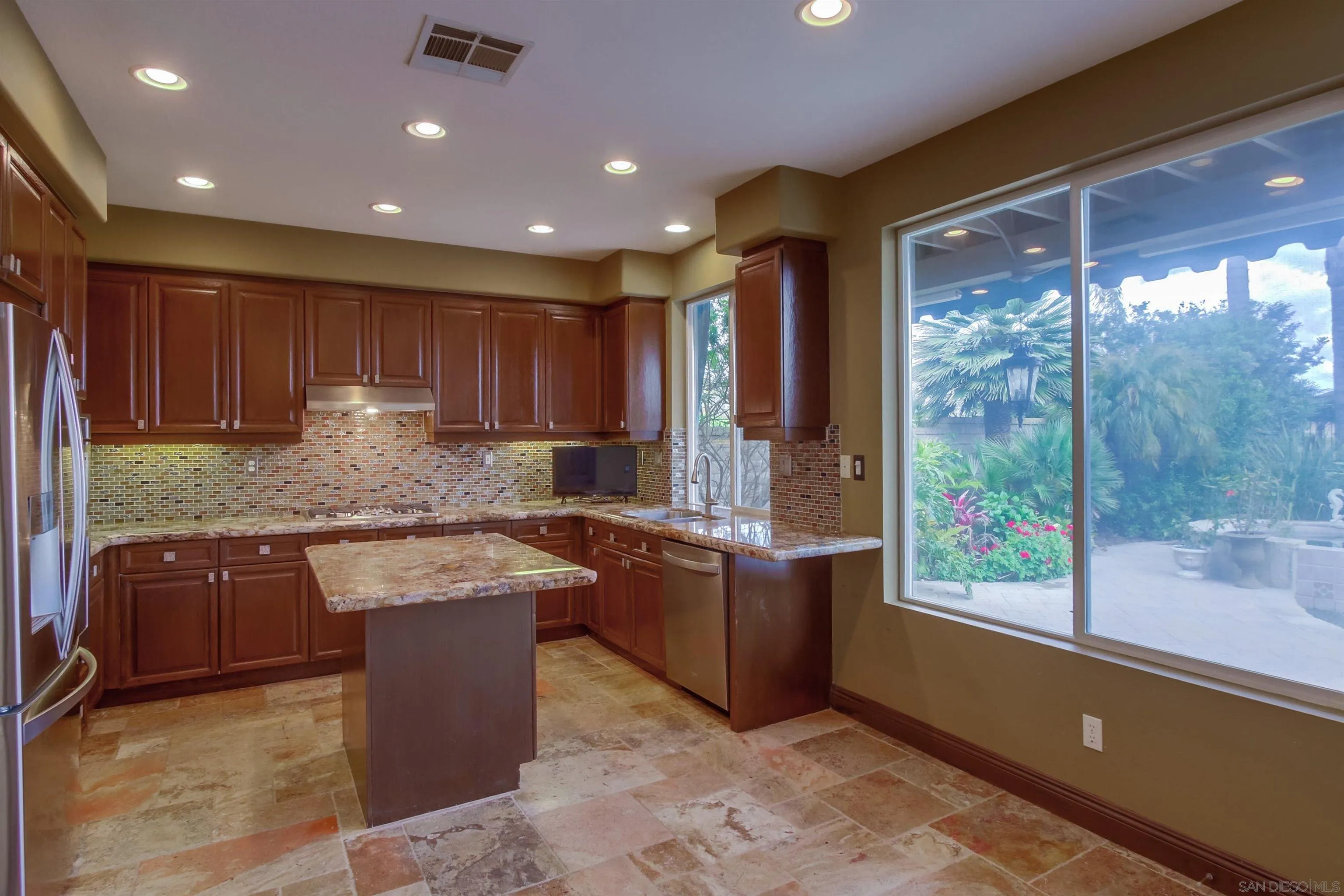 6550 Windward Ridge Way San Diego, CA 92121 - Photo 25 of 64 a kitchen with kitchen island granite countertop wooden cabinets a sink and a stove