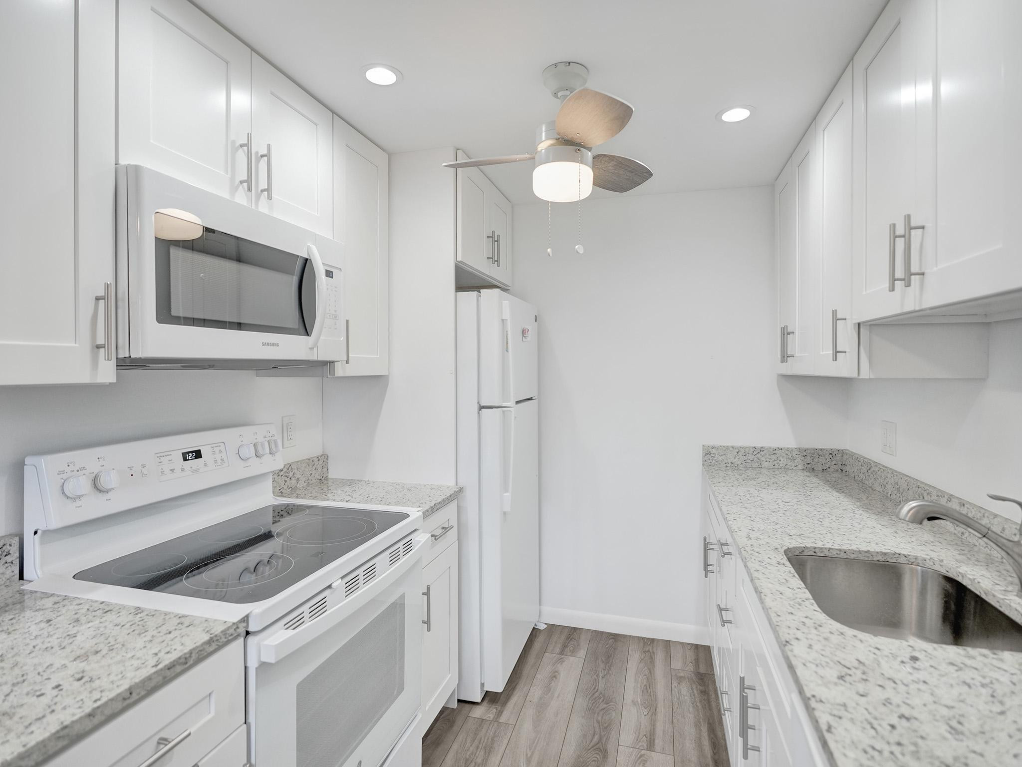 1031 Exeter, Unit 1031 Boca Raton, FL 33434 - Photo 6 of 24 a kitchen that has a sink and a stove top oven sitting inside of it