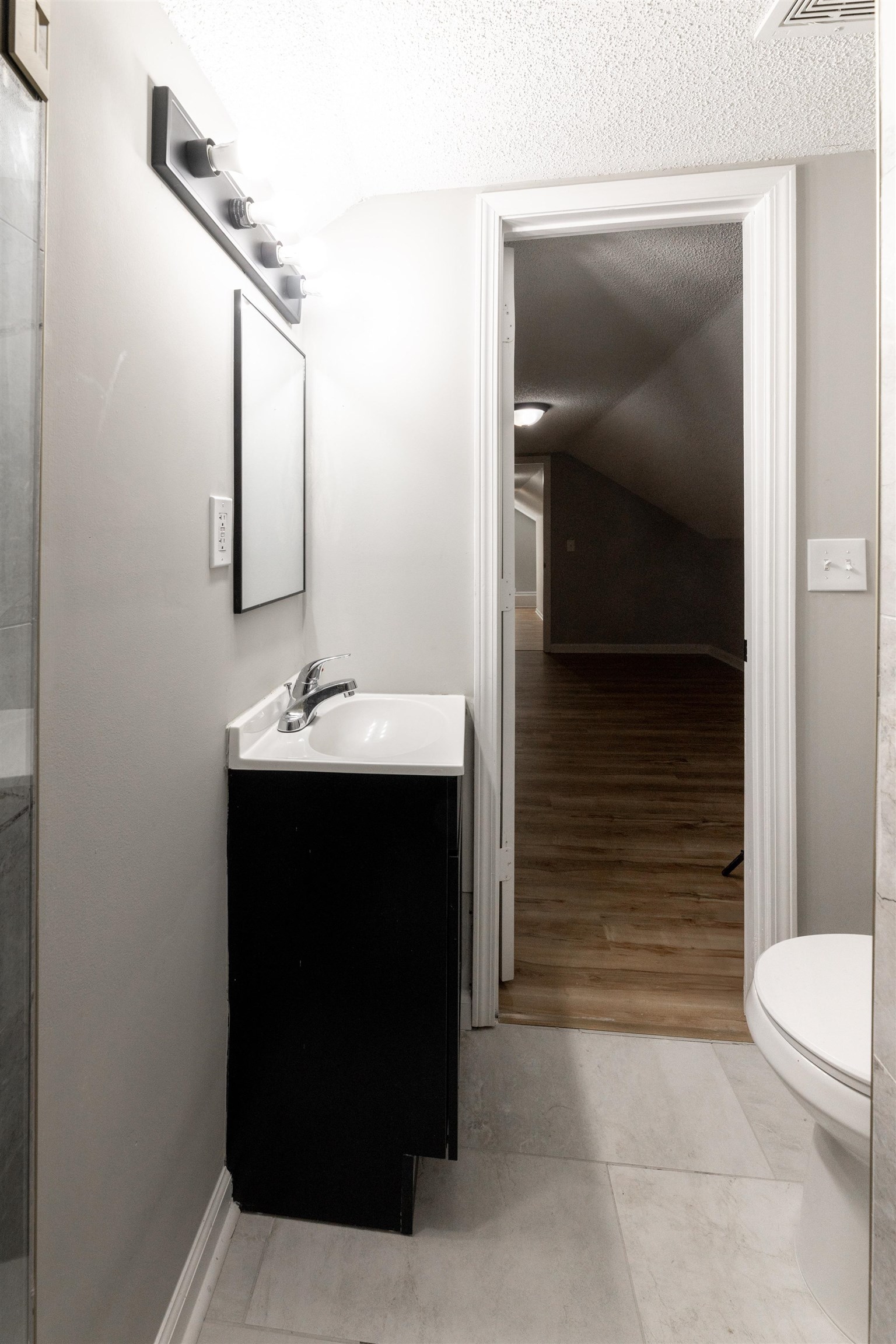 7421 Richmond Road Memphis, TN 38125 - Photo 37 of 39 Bathroom featuring a modern black vanity with a white countertop and integrated sink, a rectangular mirror, and a contemporary four-bulb vanity light fixture