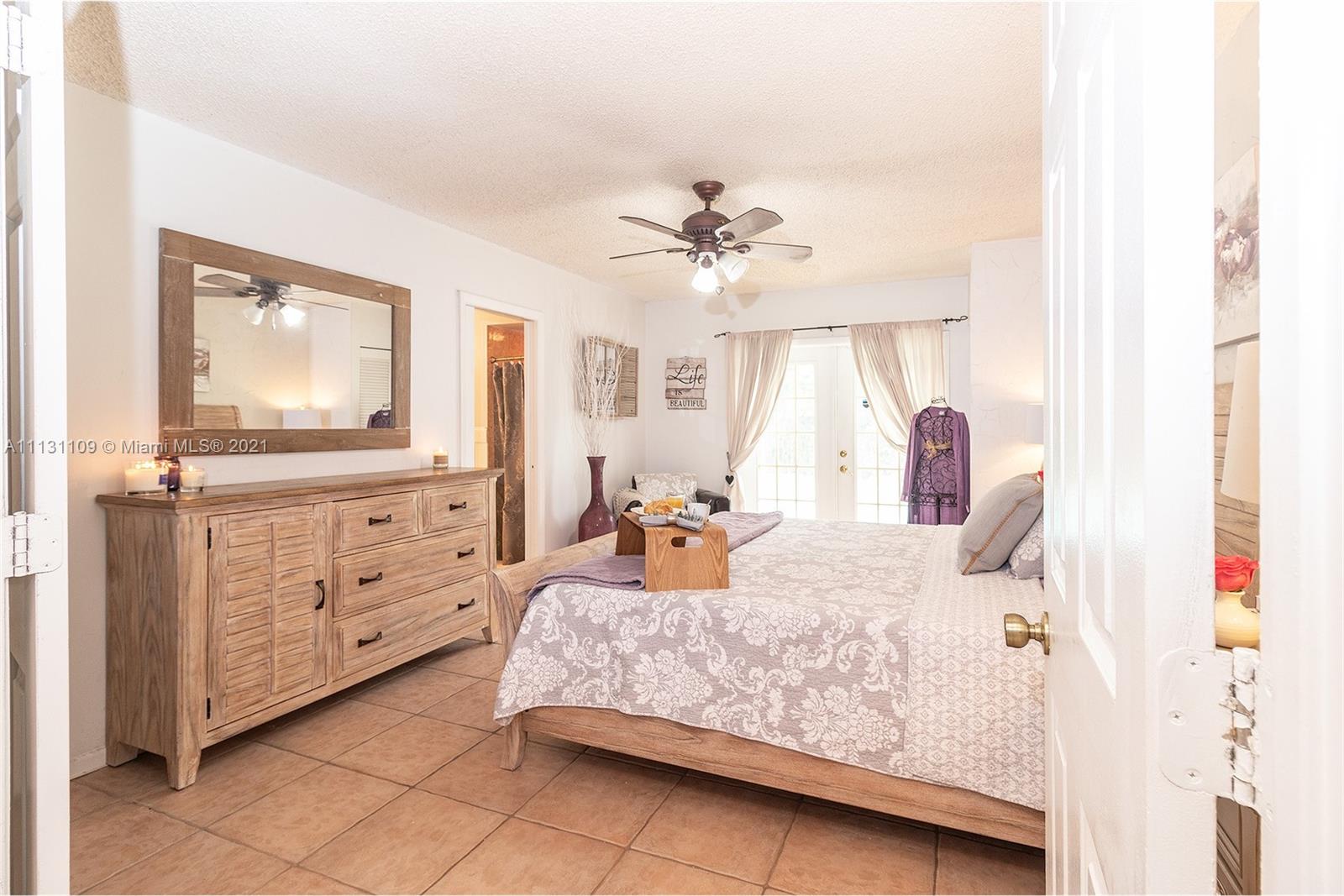 9248 Neptunes Basin Court Boca Raton, FL 33434 - Photo 21 of 34 a bedroom with a bed a chandelier and dresser
