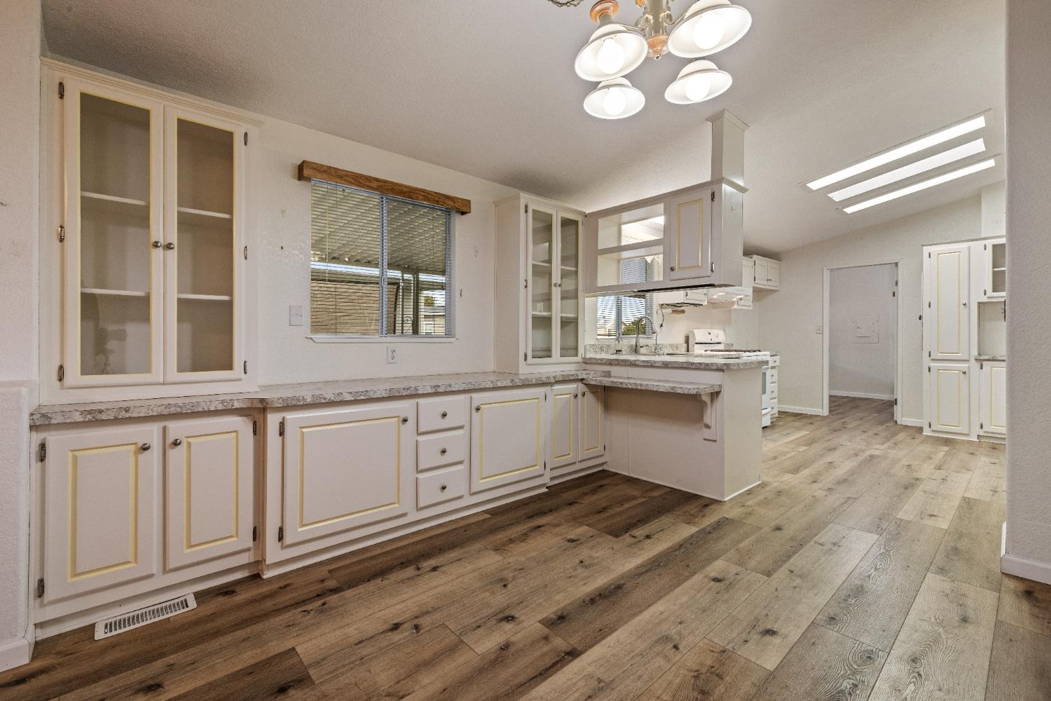 2621 Prescott Road, Unit 87 Modesto, CA 95350 - Photo 10 of 31 a large white kitchen with a large window wooden floor and stainless steel appliances