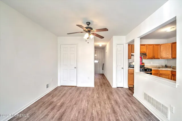 a view of a kitchen with a stove cabinets a ceiling fan and wooden floor