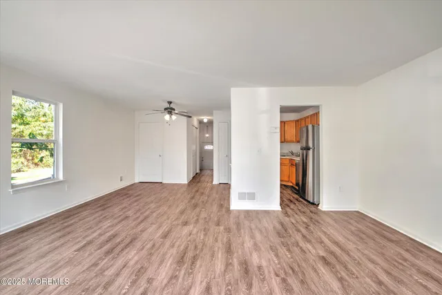 an empty room with wooden floor and windows