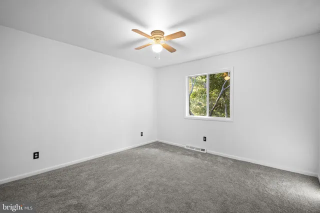 an empty room with window and ceiling fan