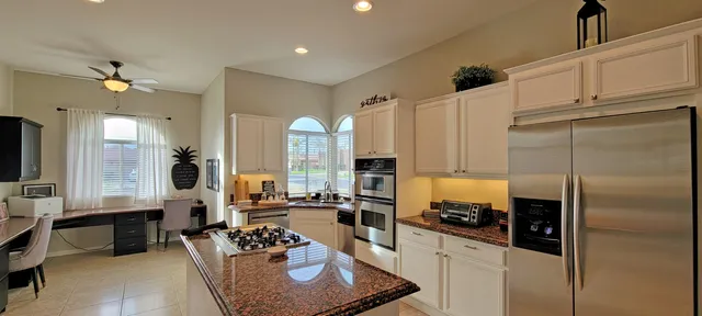 a large kitchen with a counter space a sink a refrigerator and cabinets