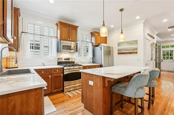 a kitchen with stainless steel appliances granite countertop stove a sink a refrigerator a dining table and chairs with wooden floor