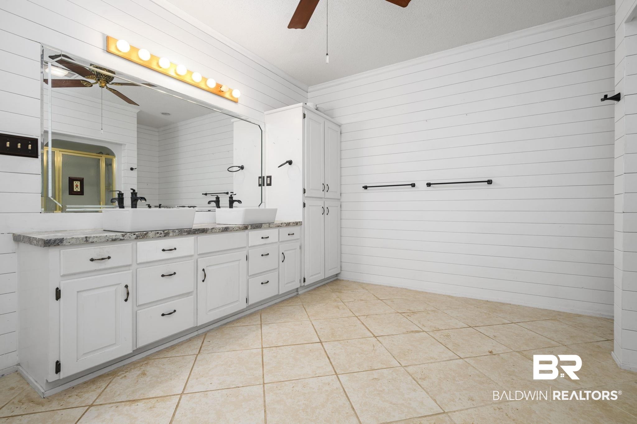 7540 2 Mile Road Irvington, AL 36544 - Photo 34 of 82 Dual vessel sinks with matte black fixtures set into a white vanity with dark hardware and a light-colored countertop