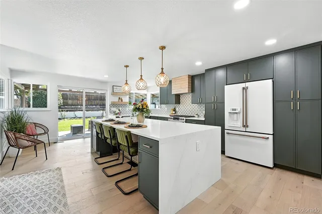 a kitchen that has a lot of white cabinets and stainless steel appliances
