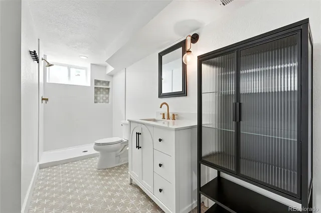 a bathroom with a toilet a sink a mirror and a shower