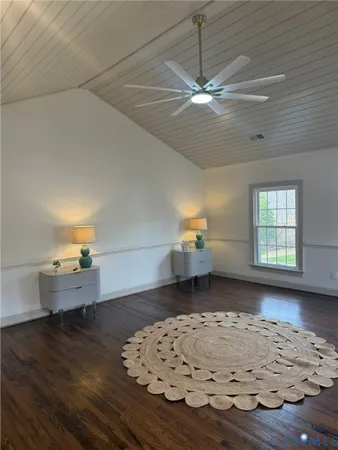 an empty room with wooden floor chandelier and windows