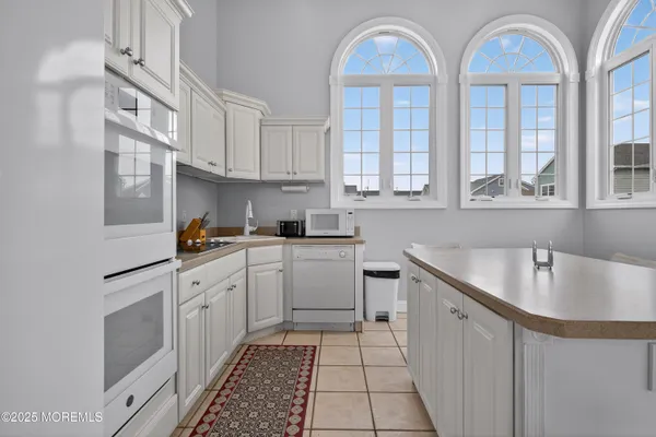 a kitchen that has a lot of white cabinets and a sink