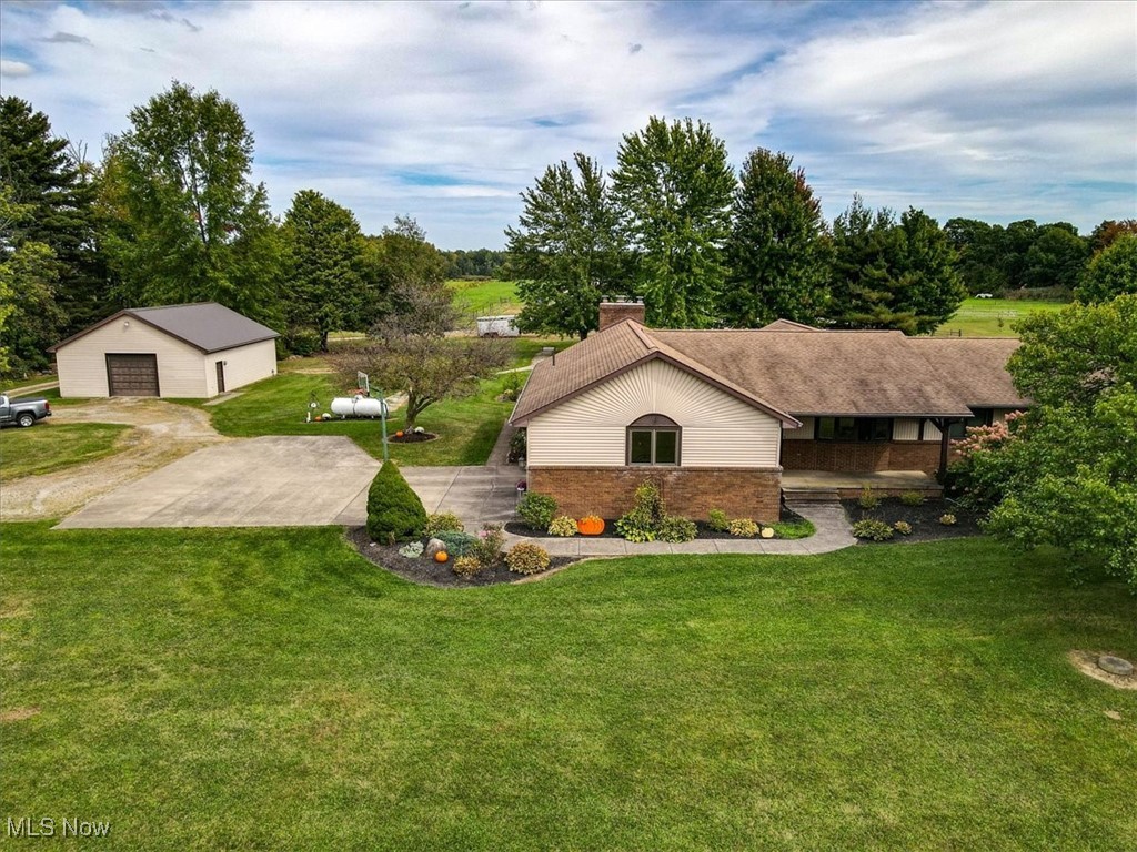 View of front facade featuring a front yard, a garage, and an outbuilding